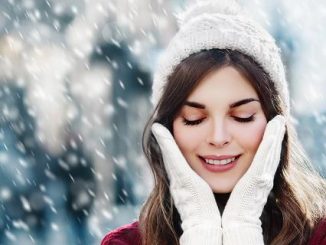 Девушка в перчатках и шапке под снегопадом